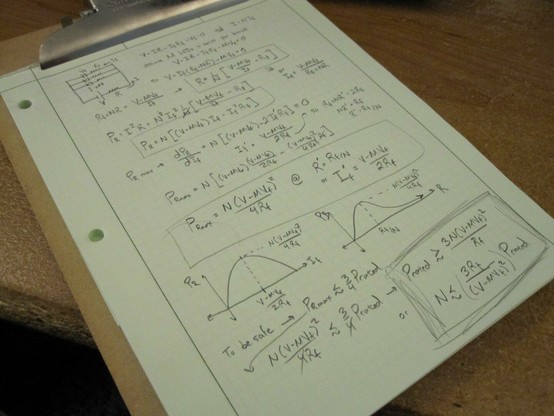 An engineer's pad showing a computation for a particular LED circuit. On a wooden chipboard clipboard and a wooden desk.