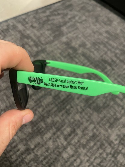 Green armed sunglasses with this printed on the side LAUSD Local District West Westside Serenade Music Festival