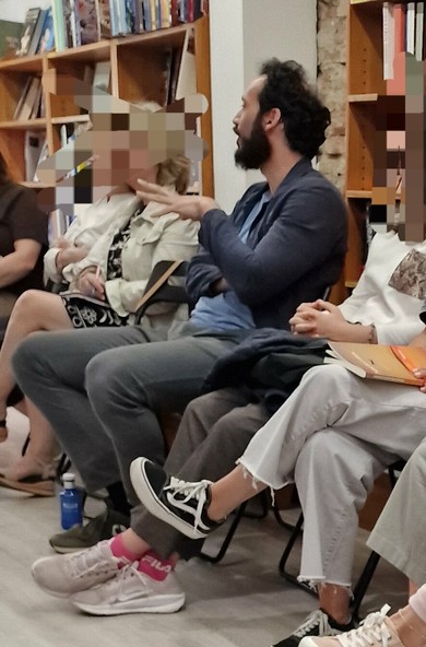 Una imagen de un grupo de personas sentadas en sillas en una librería. Un hombre con barba, Rodrigo Blanco Calderón, está sentado en el centro, hablando para la audiencia que le rodea (cuyas caras he censurado por respeto).

Al fondo se ven estantes repletos de libros. La imagen es de la charla sobre el libro Venecos en el club de lectura de librerías Luces.