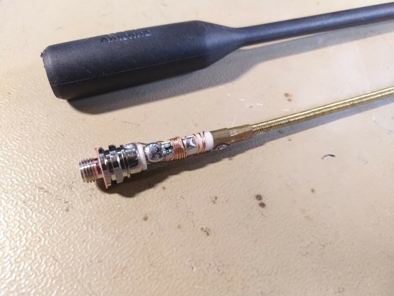 Picture shows the black empty shell of a handheld radio rubberduck antenna. With it's insides displayed below it.