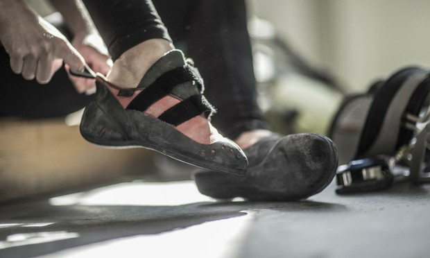 Una persona calzándose las zapatillas de escalada en el gimnasio (John Fedele / Blend Images vía Getty Images)