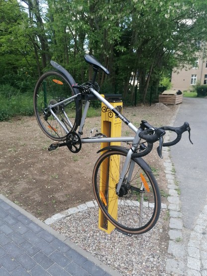 Gelbe Fixit Station mit silbergrauem Fahrrad.