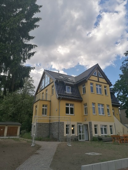 Der Jugendclub: Gelbes Fachwerkhaus mit Feldsteinsockel und Erker in einem parkähnlichen Garten