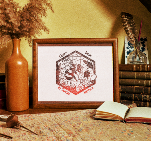 Linogravure en rouge et noir avec un bourdon qui butine des fleurs anarchistes. La linogravure est placée dans un cadre au milieu de vieux livres, petits objets et décorations à l'ambiance chaude et vintage.