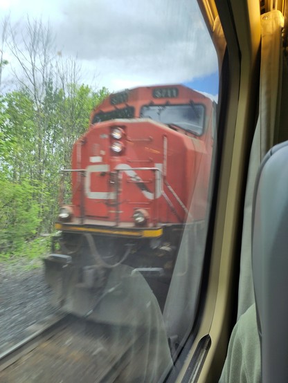 Foto. Eine rote Lokomotive im Zug-Fenster.