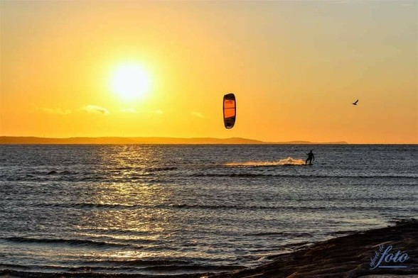 Am rechten Rand seht ihr noch ein Stündchen der Mole, blaues, seichtes Ostseewasser mit einem Kitesurfer und einer frechen Fotomöwe. Im Hintergrund die Küste bis zum Seebad Koserow sichtbar im goldgelben Sonnenuntergang.