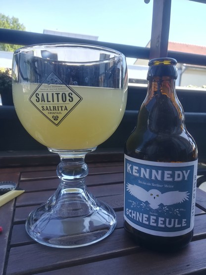 Eine Flasche Schneeeule Kennedy mit dem Slogan "Ick bin ein Berliner Weiße", deren Inhalt in ein Kelchglas eingeschenkt wurde.