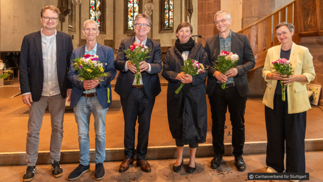 Minister Manne Lucha und fünf weitere Personen in einer Kirche, fünf halten Blumensträuße, alle lächeln und stehen nebeneinander vorne im Gebäude.