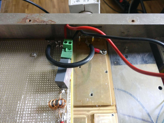 Gros plan sur le connecteur d’alimentation de la carte d‘amplification, avant modification. On voit que les deux fils rouge et noir passent près du connecteur HF (mal visible, dans l’ombre), ce qui générait des parasites.