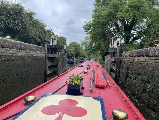 Narrowboat with red roof going through lock gate.