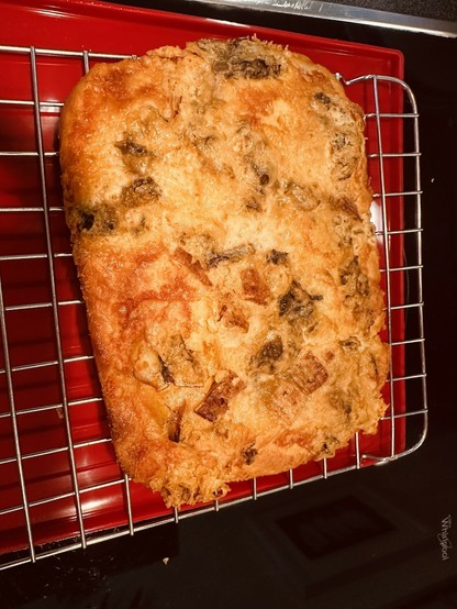 A freshly baked focaccia bread with blue cheese sits on a cooling rack.