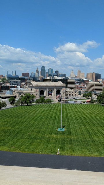 Verdant lawn with the tall downtown buildings behind. Sunny day, with few clouds in the sky.
