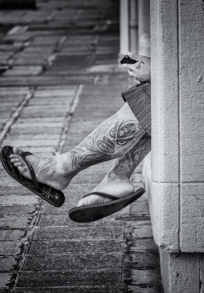 Pair of tattooed calves sticking out from the side of a building in Honolulu's Chinatown.