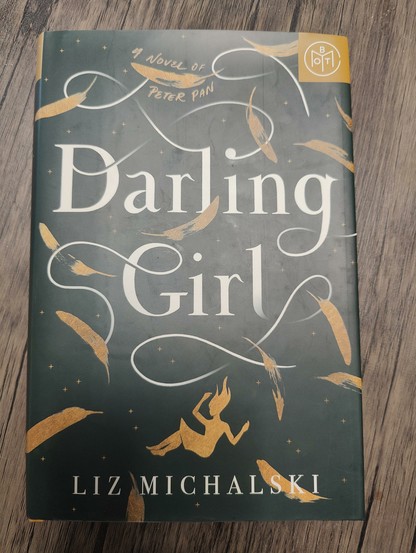 Cover of Darling Girl by Liz Michalski. Cover is black with gold feathers and a girl falling along the bottom. Writing is in white.