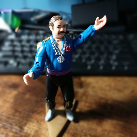 6 inch action figure of Harry Mudd. He has a busy mustache and a comb over hairstyle. He wears a blue shirt with golden shoulder tassels and silver medallions around his neck. He has a purple sash around his waist and black pants.