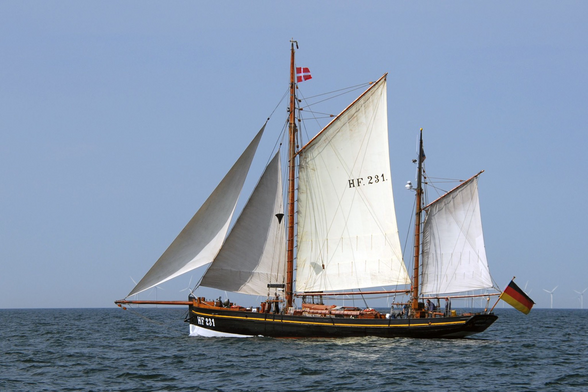 Hochseekutter HF231 "Landrat Küster" in Fahrt auf offener See, unter Groß- und Besansegel, Fock und Klüver. Oben am Mast weht die dänische Gastlandflagge, am Heck die Flagge der Bundesrepublik Deutschland.
