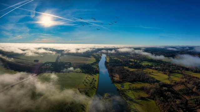 Ein Luftbild der Stadt Henley-on-Thames umgeben von grünen Feldern und Wasser.