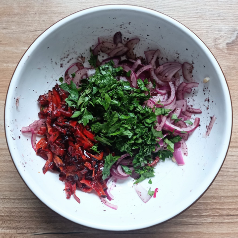 In der Schüssel Zwiebeln, in Streifen geschnittene Paprika und gehackte Petersilie