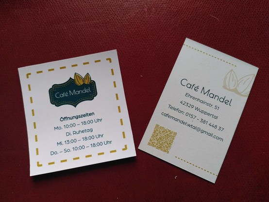 visitenkarten auf rotem untergrund
text: 
café mandel 
öffnunngszeiten
mo. 10:00 - 18:00 uhr
di. ruhetag
mi. 13:00 - 18:00 uhr
do. - so. 10:00 - 18:00 uhr

café mandel
ehrenhainstr. 51
42329 wuppertal
telefon: 0157 - 381 448 37
cafemandel.wtal@gmail.com