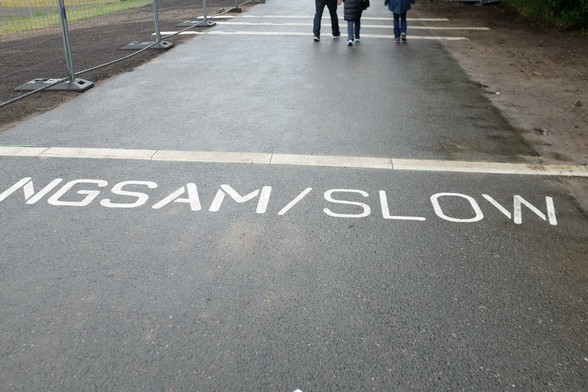 Bremsschwelle mit auf der Fahrbahn aufgemaltem "LANGSAM / SLOW".