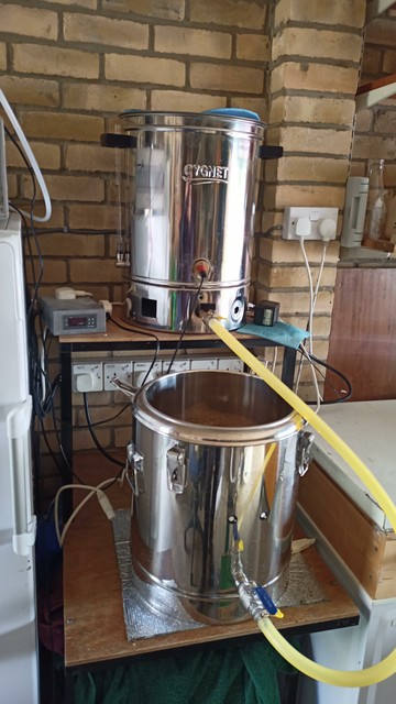 The stainless urn has a pipe connecting it to another urn above it on a small platform.