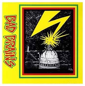 The image features the album cover of "Bad Brains" by the punk band Bad Brains. It displays a stylized illustration of the U.S. Capitol dome with a lightning bolt and radiating stars, set against a yellow background and bordered with green and yellow stripes.