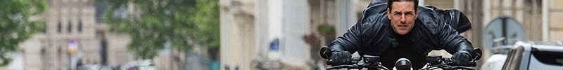 The top half of an image of Tom Cruise riding a motorcycle toward the camera.