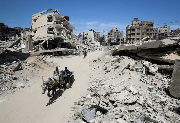 Palestinians ride a donkey cart past the rubble of houses in Gaza City.
