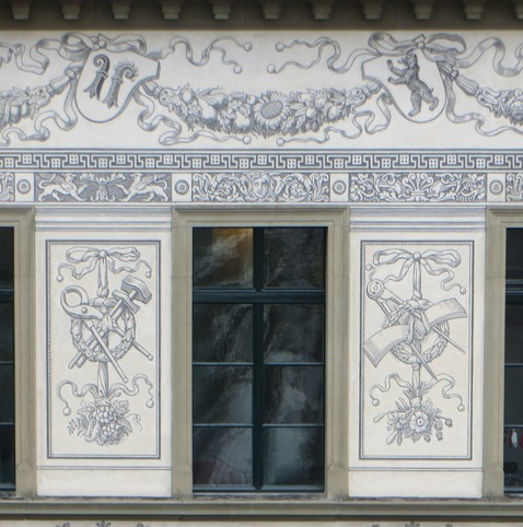 Detail of a window with illustrations of various tools. Above are the coats of arms of several Swiss cantons.