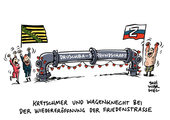 Eine mit roten Herzchen geschmückte Gasleitung führt von Z-Russland mit dem blutverschmierten, jubelnden Putin nach Sachsen, wo sich Kretschmer und Wagenknecht freuen wie Bolle. Auf dem Rohr steht „DRUSCHBA - FREUNDSCHAFT“. Unterzeile: „KRETSCHMER UND WAGENKNECHT BEI DER WIEDERERÖFFNUNG DER FRIEDENSTRASSE“ (Credit: SCHWARWEL)