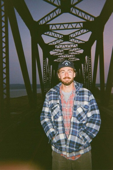 Marshall Veroni the folk singer, standing on a bridge at dusk.