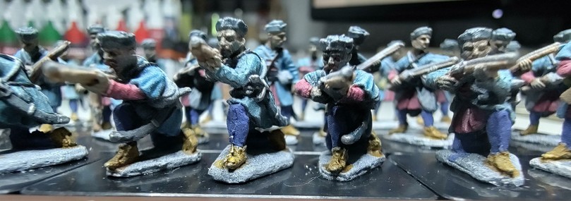 A close up of minis of kneeling infantry aiming down halfmuskets