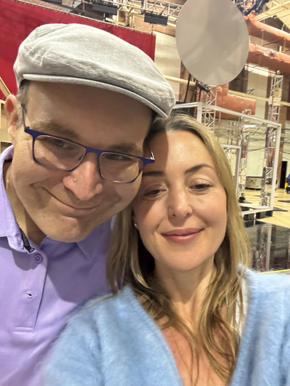 Ljova and the composer Paola Prestini, on the set of Prestini's opera "Sensorium Ex". Ljova is wearing a purple shirt and a grey cap; Prestini is wearing a blue sweater. It's a selfie and they're smiling.