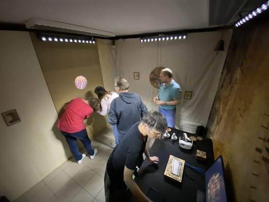 5 personnes observent différents objets dans une pièce.