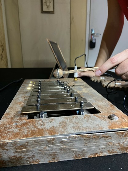 Une main avec une mailloche joue sur un petit xylophone.