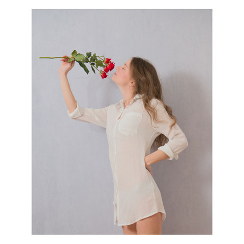 Female model smelling the aroma of a bunch of red roses