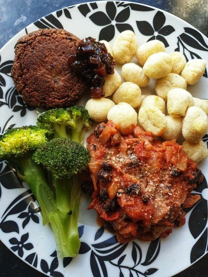 A plate with the meal on it.
Top L: Baked Black Bean & Walnut Burger with 'Branston Pickle'
Top R: Baked Potato Gnocchi 
Lower R: Black Bean, Onion & Tomato Chilli sauce
Lower L: Steamed Broccoli