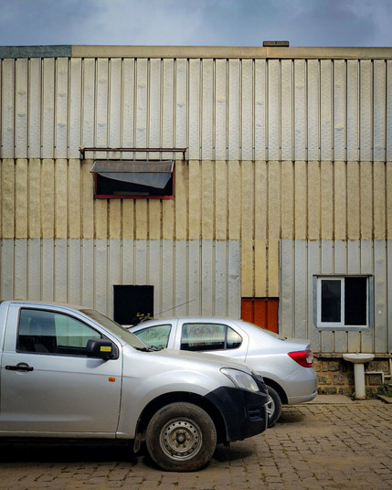 Deux voitures garées devant un hangar rapiécé, et un lavabo égaré.