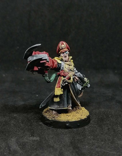 A metal minaiture of Yarrick, who has a storm bolter in his left hand and a ork power klaw in his right one. He has a red cap and a black coat and a robotic eye.