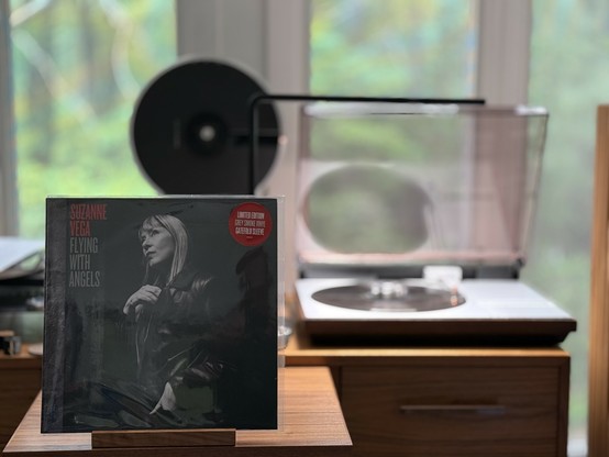 Suzanne Vega - Flying with Angels LP cover.

A black and white photo of Suzanne, looking to the left...towards the artist and title.

The "smoke" colored LP plays on a vintage, restored Bang & Olufsen Beogram 4000 linear-tracking turntable to the right.