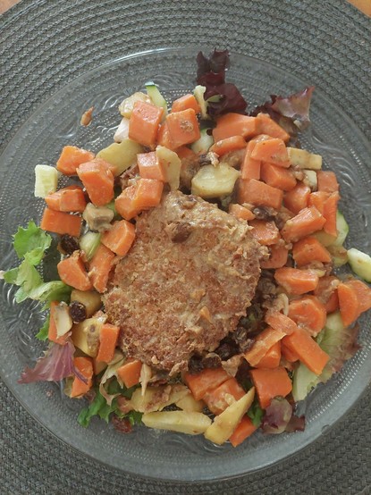 Assiette repas végétalienne posée sur un set de table gris 
Jour de courses ... j' avais encore beaucoup de carottes et j' en ai repris !!! Alors cuisson al dente et ajout de petite pomme dans un bouillon cube végétal. Ensuite le tout poêlé rapidement avec steak végétal de soja,seitan, crème de soja, quelques raisins  secs, un beau champignon de panam, un petit trait tamari. Quelques feuilles de salade et concombre frais
Pain levain