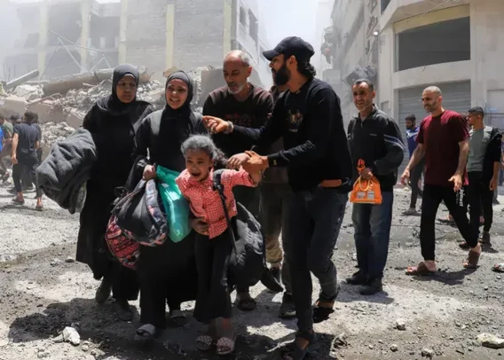 A Palestinian family fleeing Gaza City, including a terrified young girl holding a few bags with her belongings.