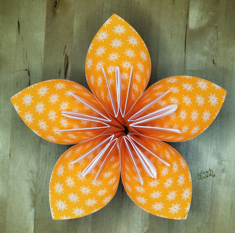 Photo of an orange kusudama flower sitting upright.
