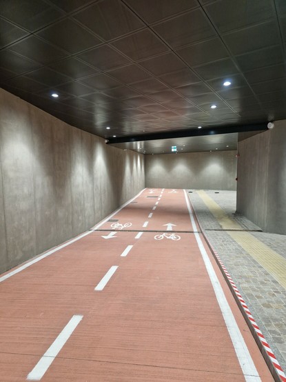 Zwei Fahrradspuren auf rotem Grund enden an einer Betonwand.