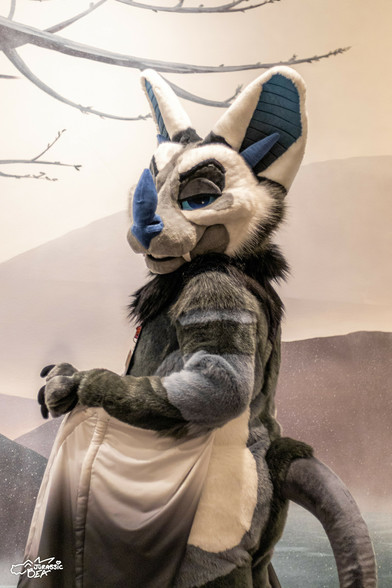 A photo of a bat fursuit looking over their shoulder at the viewer.