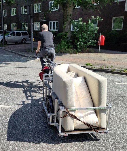 Fahrrad mit großem Anhänger #TrudeTrailer, der mit allerlei Gerümpel beladen ist.