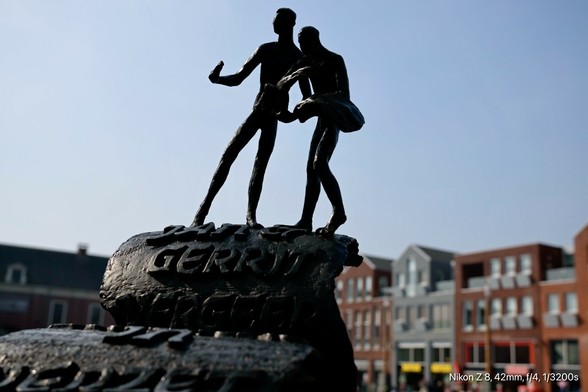 Das Bild zeigt eine Bronzestatue von zwei männlichen Figuren, die auf einem steinernen Sockel stehen. Die Figuren sind in einer dynamischen Pose dargestellt, wobei einer der Figuren den anderen auf dem Arm trägt. Der Sockel trägt die Inschrift "GERRY MERKEL". Im Hintergrund sind moderne Gebäude mit roten und grauen Fassaden zu sehen, die in einem urbanen Umfeld liegen. Der Himmel ist klar und blau. Die Statue ist im Vordergrund scharf, während der Hintergrund leicht verschwommen ist.

Bereitgestellt von @altbot, privat und lokal generiert mit Ovis2-8B

🌱 Energieverbrauch: 0.152 Wh