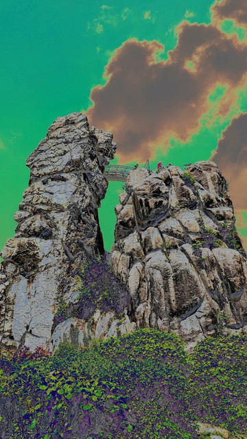 A photograph with color shift of the Externsteine. The sky is green with ochre clouds.
