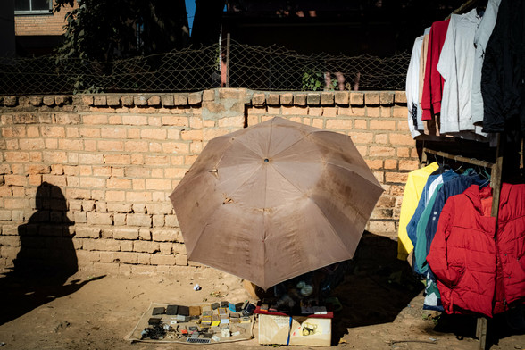 Un vendeur de rue abrité du soleil sous un parapluie