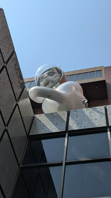 A sculpture of a white "astronaut cat" it's pretty high up on a building and the picture is taken from street level.